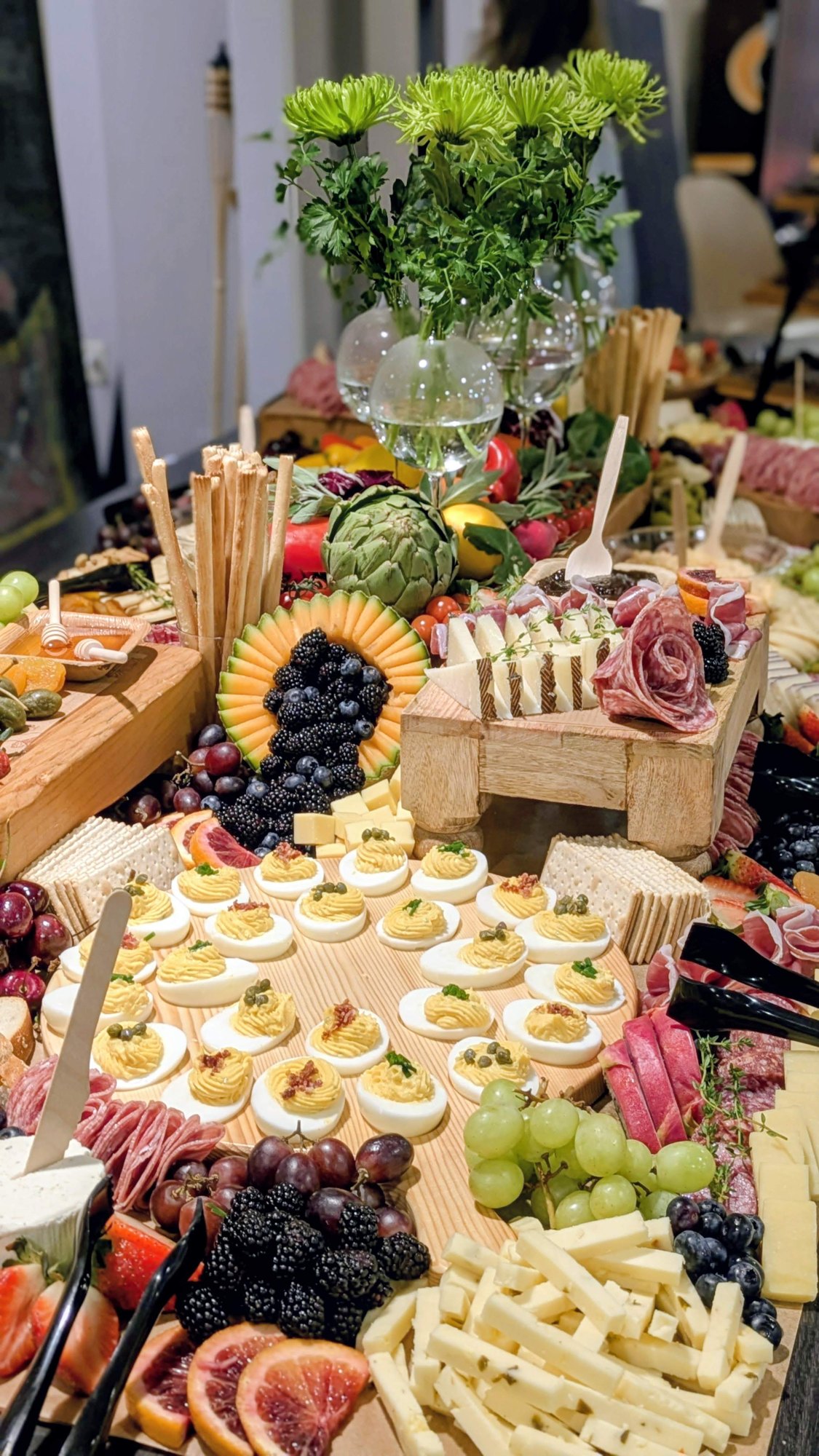 Grazing table with cheeses, charcuterie, deviled eggs and fresh greenery