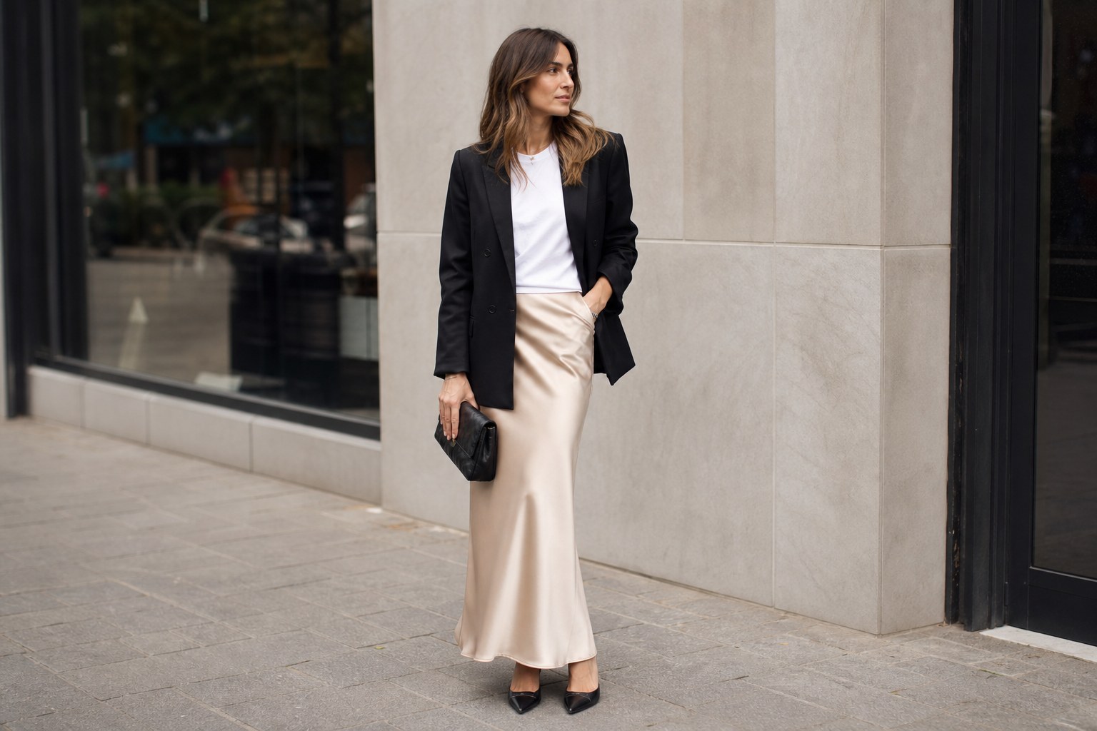 Woman styling a champagne satin skirt with a black blazer and pointed flats