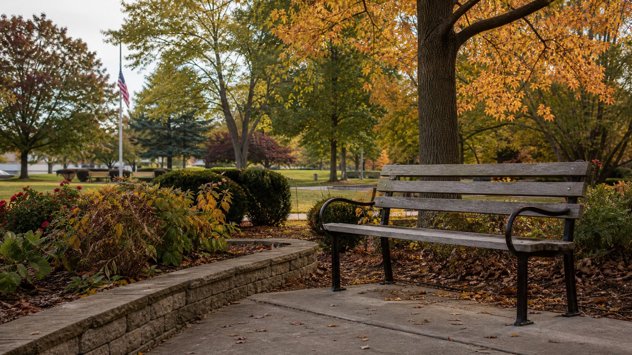 Quiet bench in a park with an American flag in the distance.