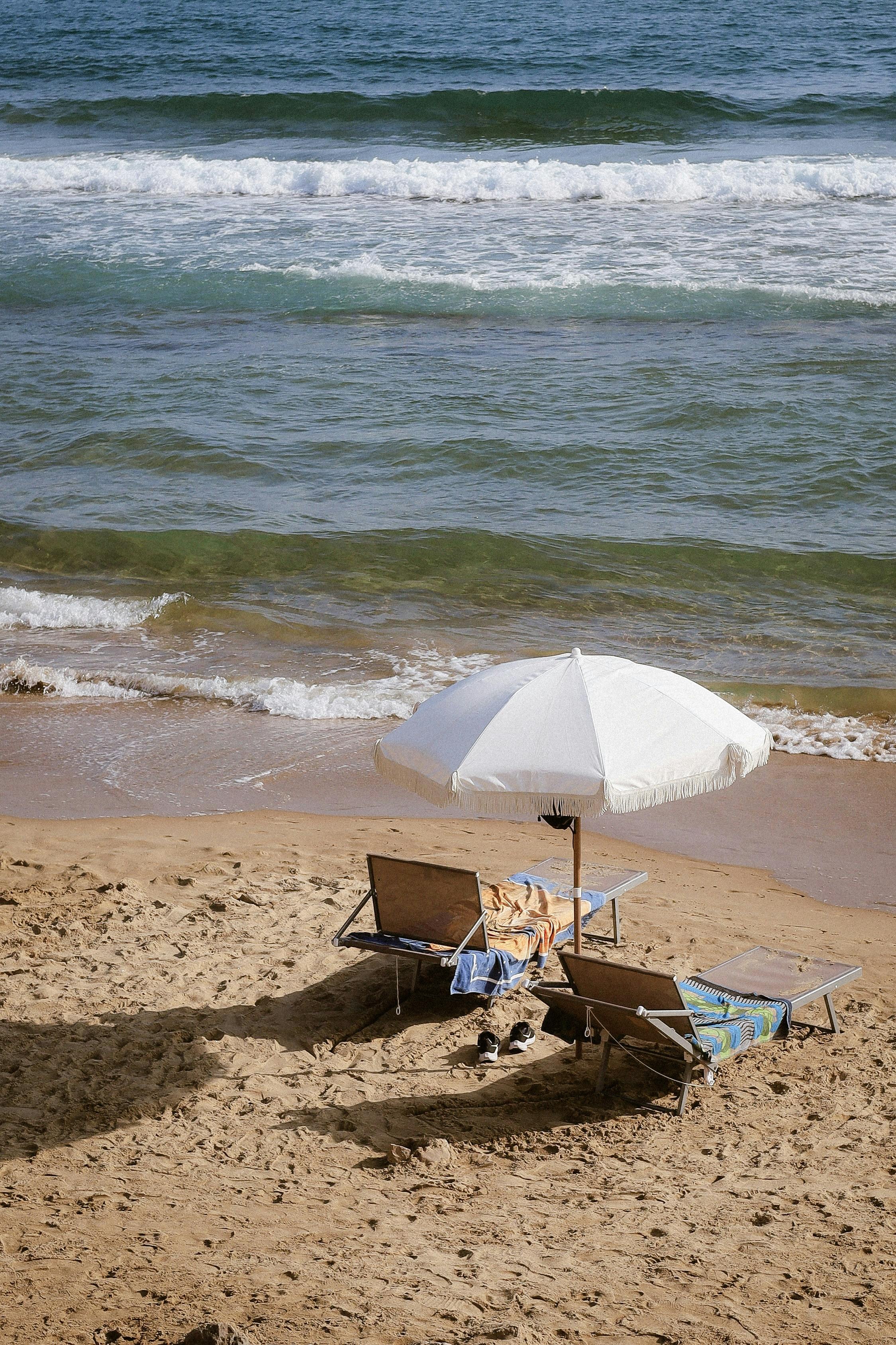Beach chairs beneath an umbrella by the sea