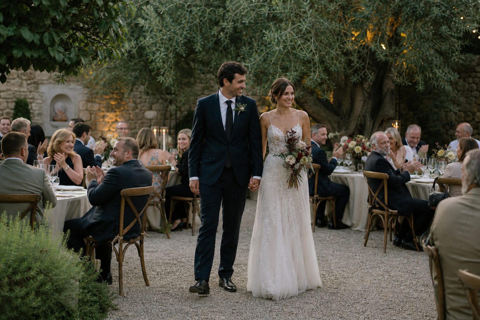 Bride and groom arriving at a garden wedding reception as guests applaud