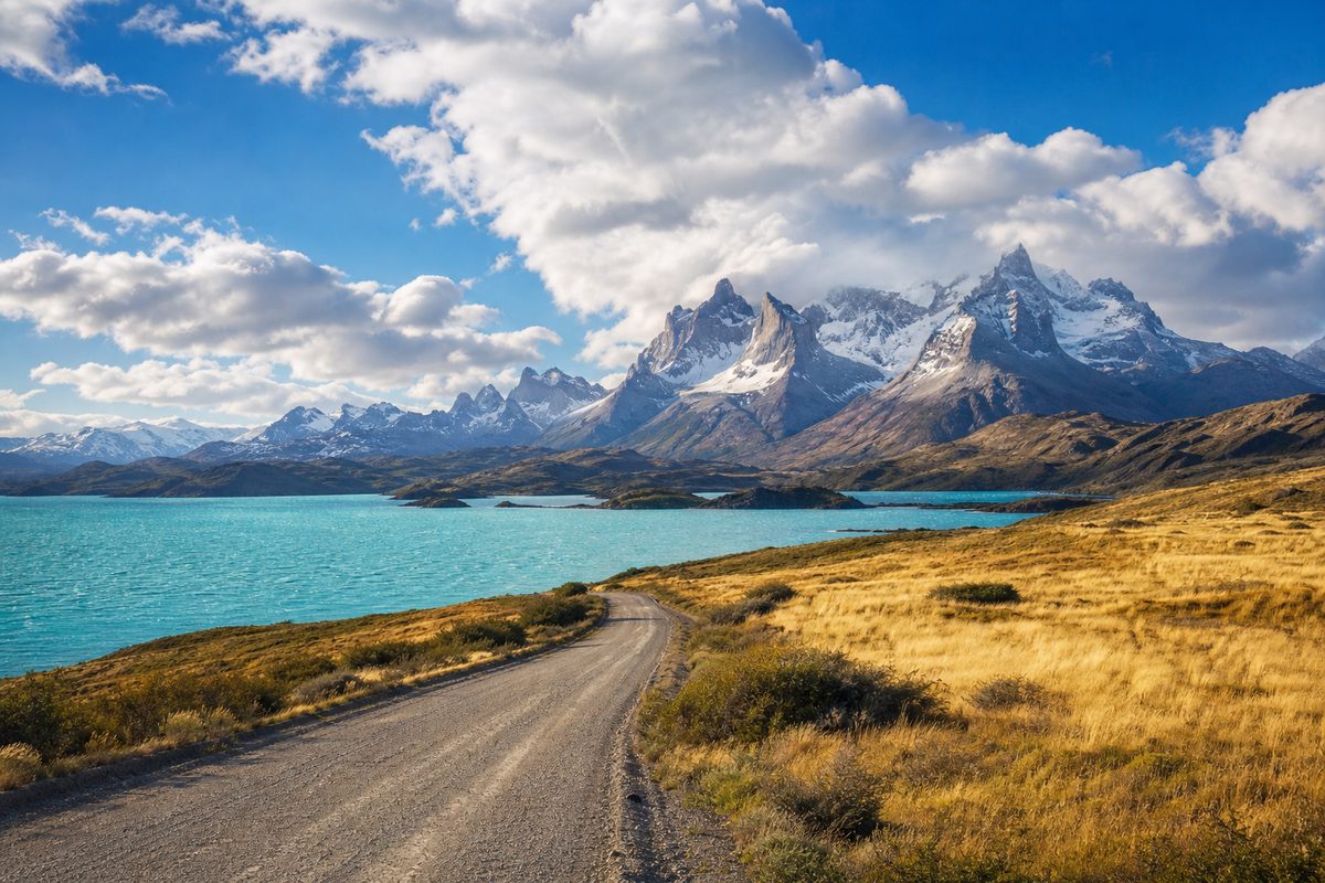 Patagonian road leading toward mountains and a blue lake