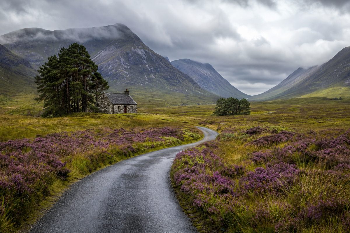 Highland road through purple heather and misty mountains