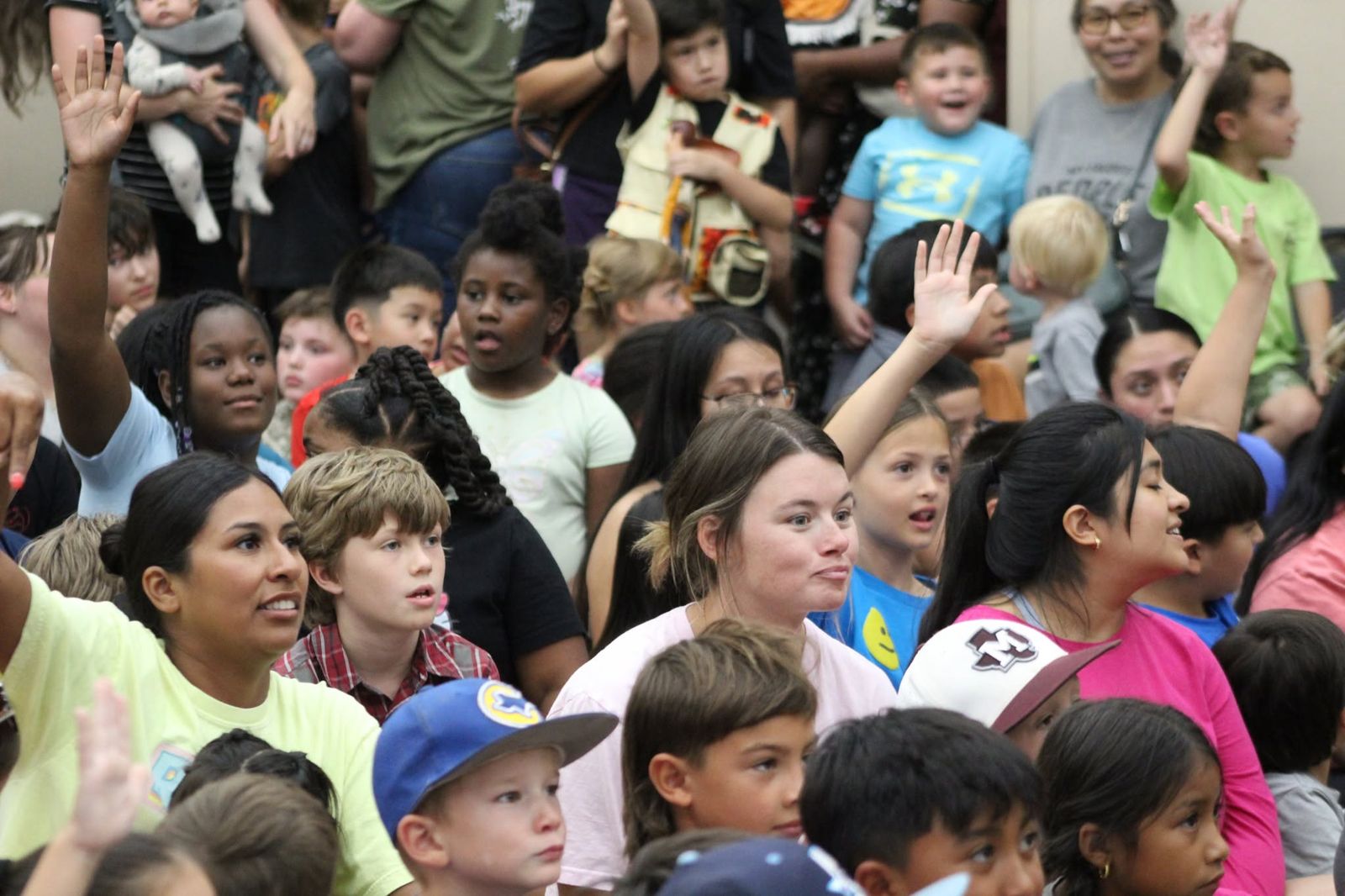 Children raising their hands during a Snake Encounters program in Corsicana