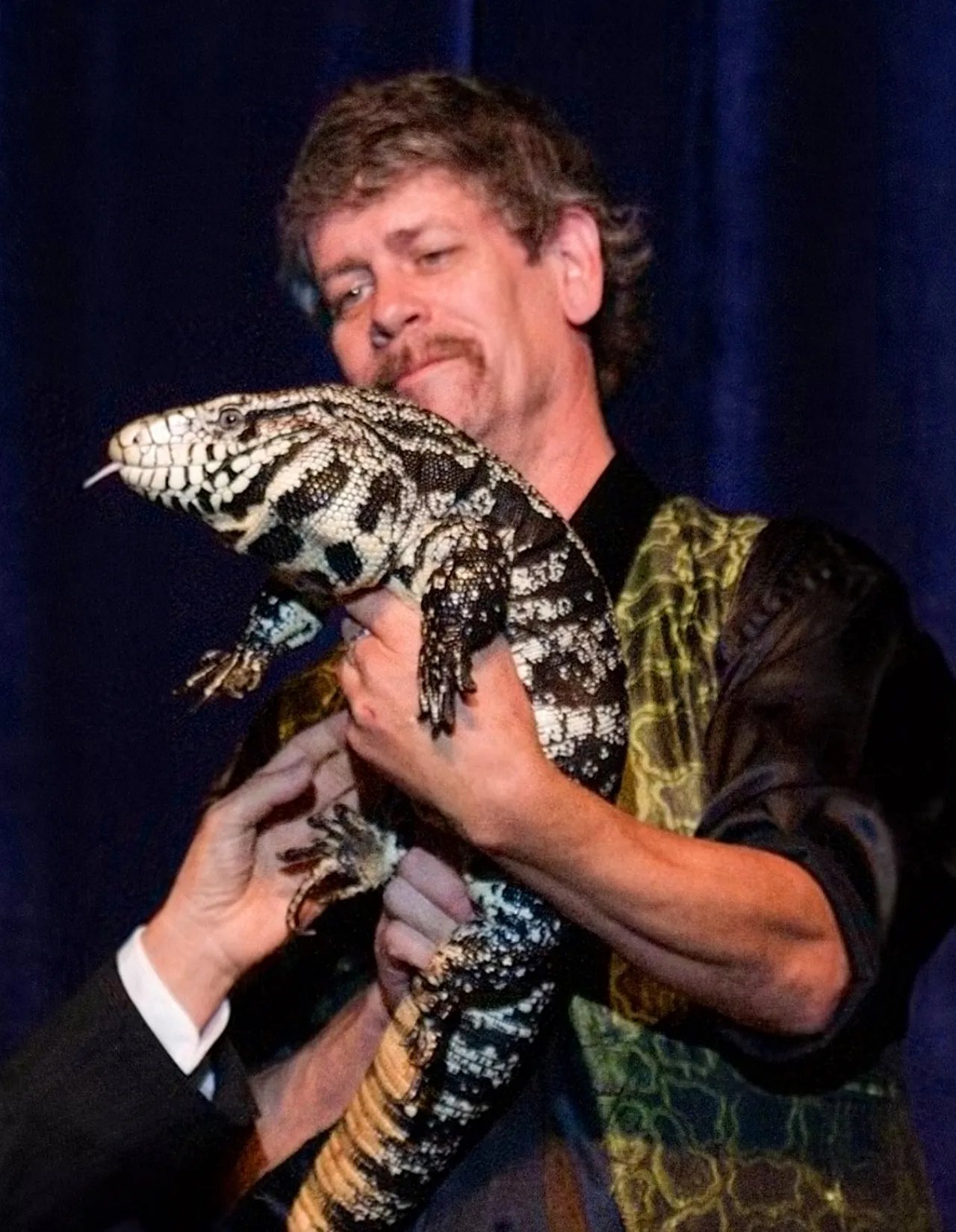 Daryl Sprout holding a live reptile during a performance