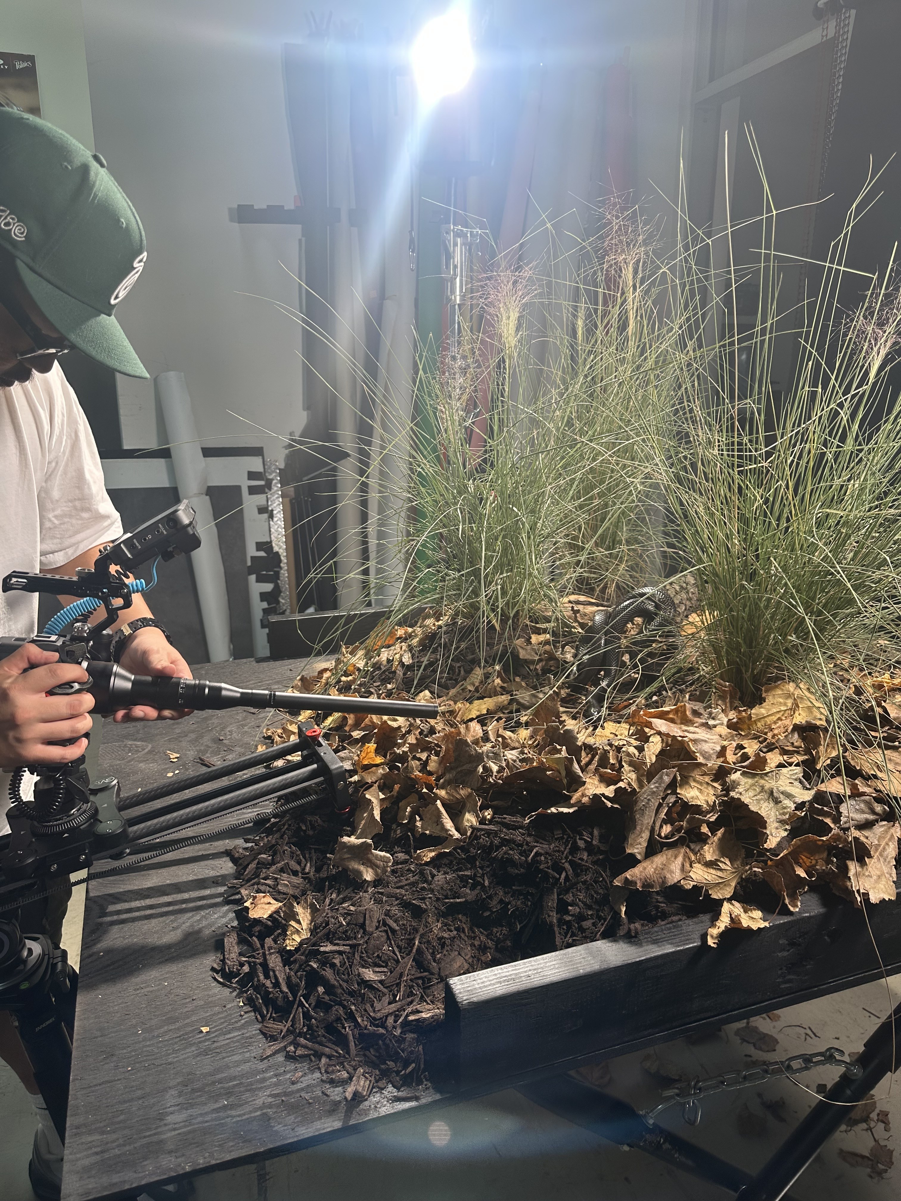 Camera operator using a probe lens beside a snake on a styled shoot set