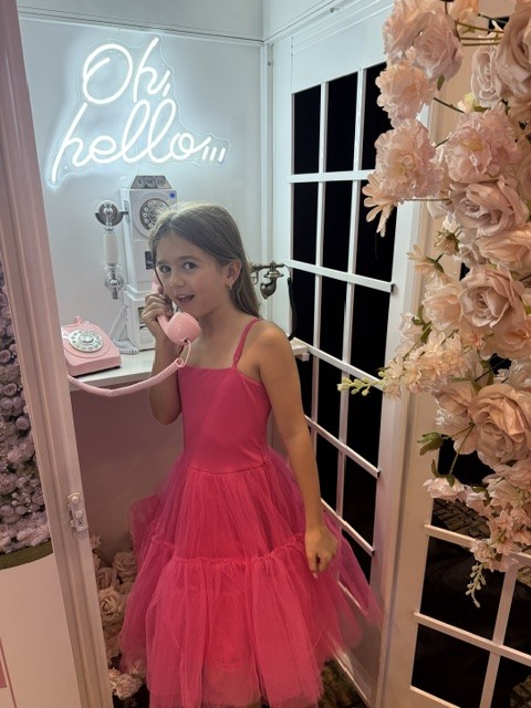 Young guest using a pink audio guestbook phone inside The Pose Garden telephone booth