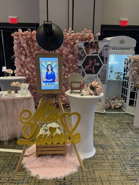 Pink flower wall and wood photo booth display from The Pose Garden at a Phoenix-area quinceañera expo