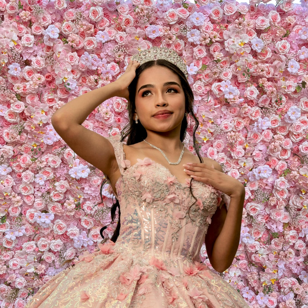 Quinceañera posing in front of a pink flower wall