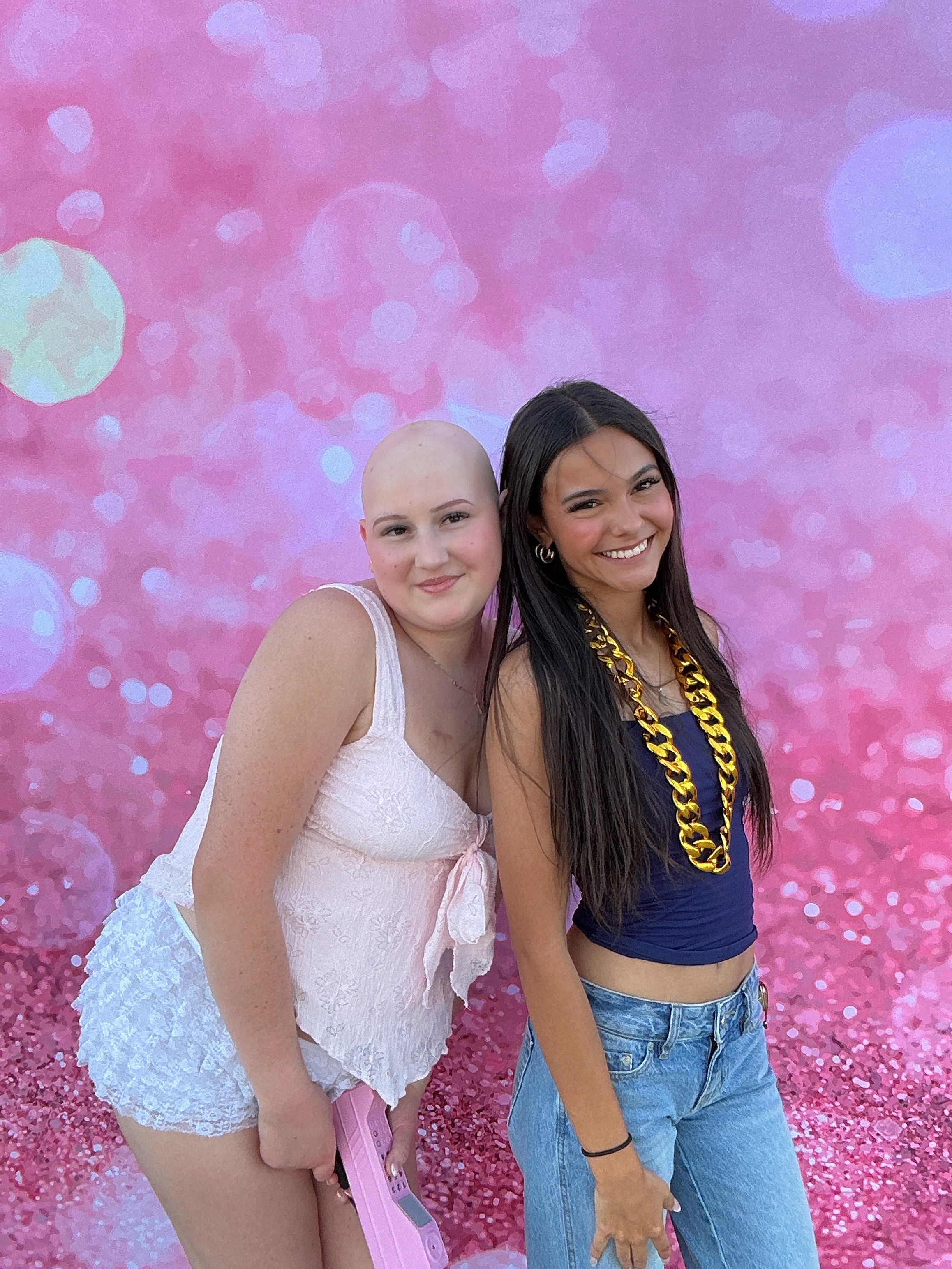 Two guests posing in front of a pink Photo Booth backdrop