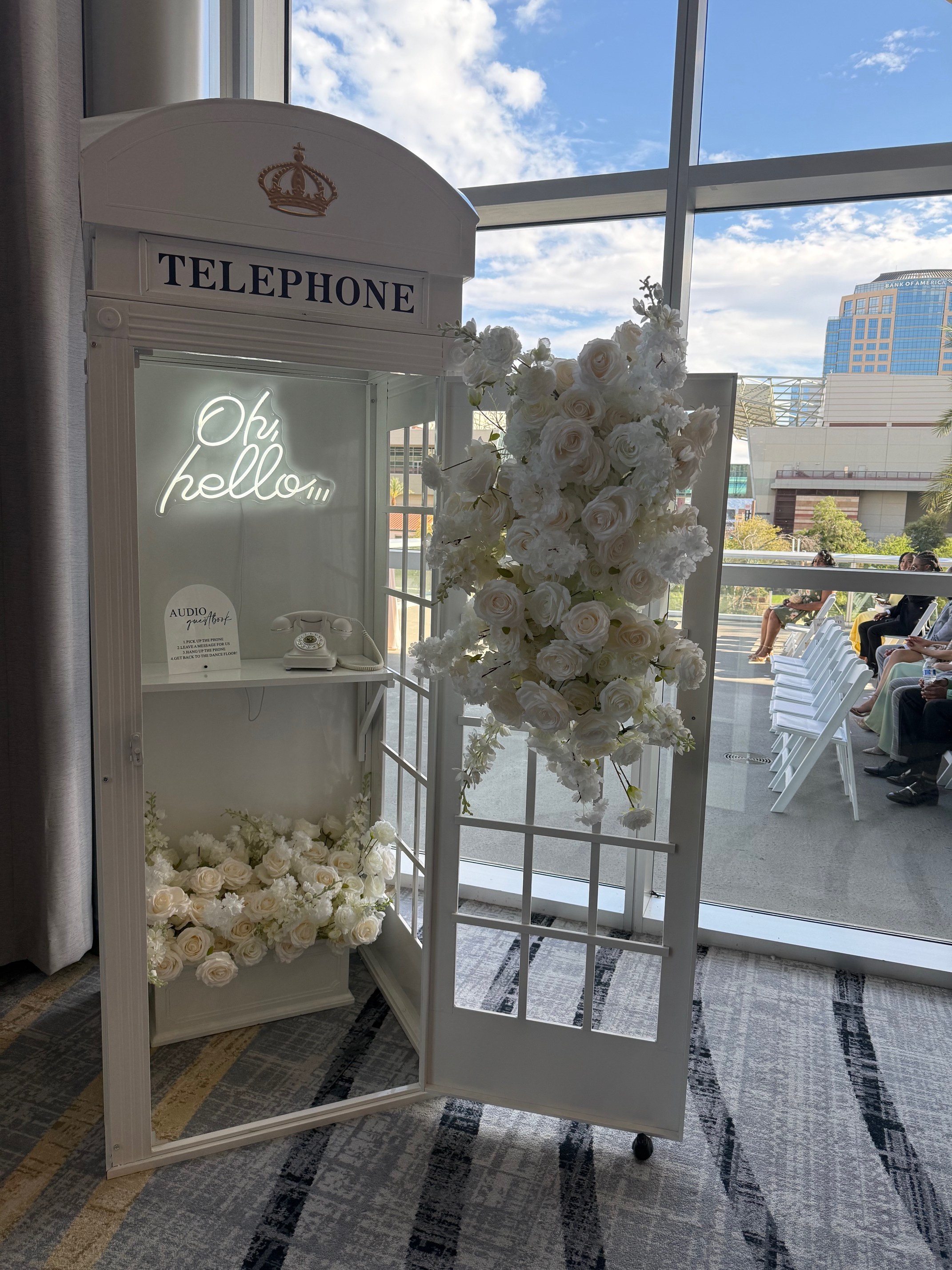 White floral telephone booth with an audio guestbook phone at a wedding