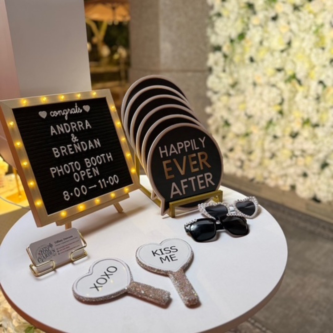 Wedding Photo Booth props arranged on a table in front of a flower wall