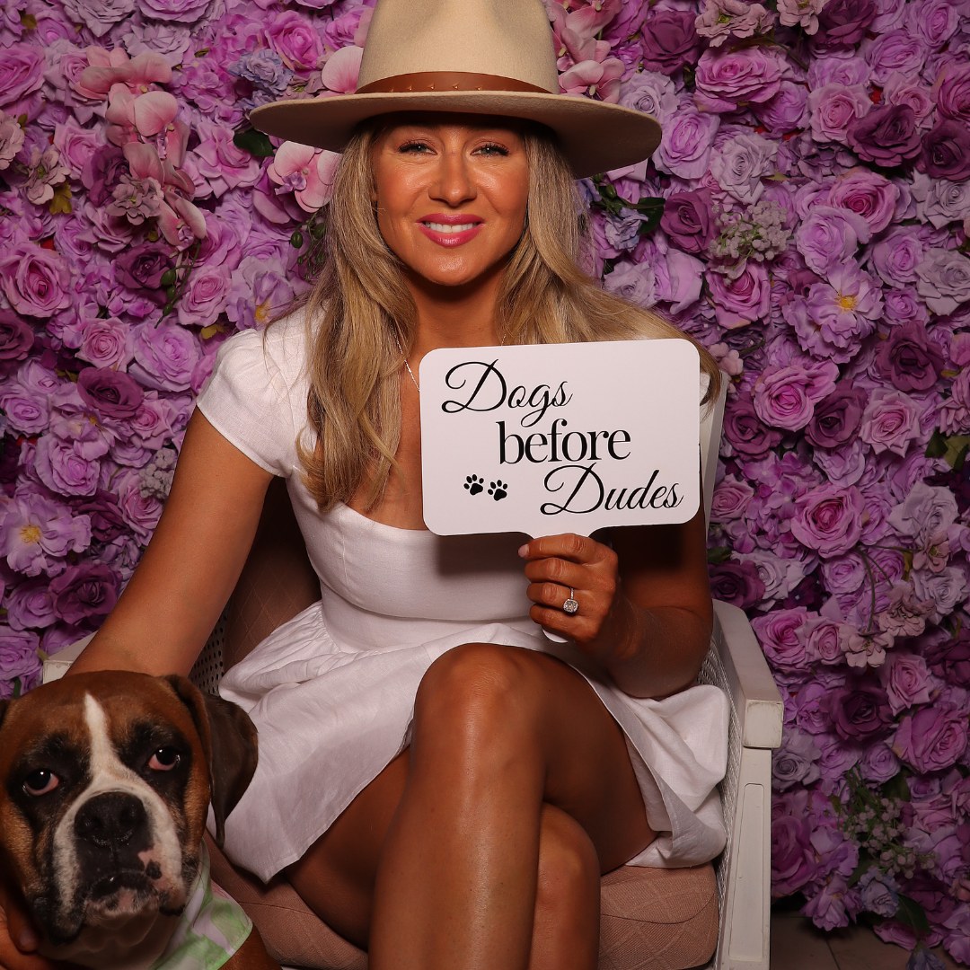 Wedding guest holding a Days Before Dudes sign in front of a flower wall