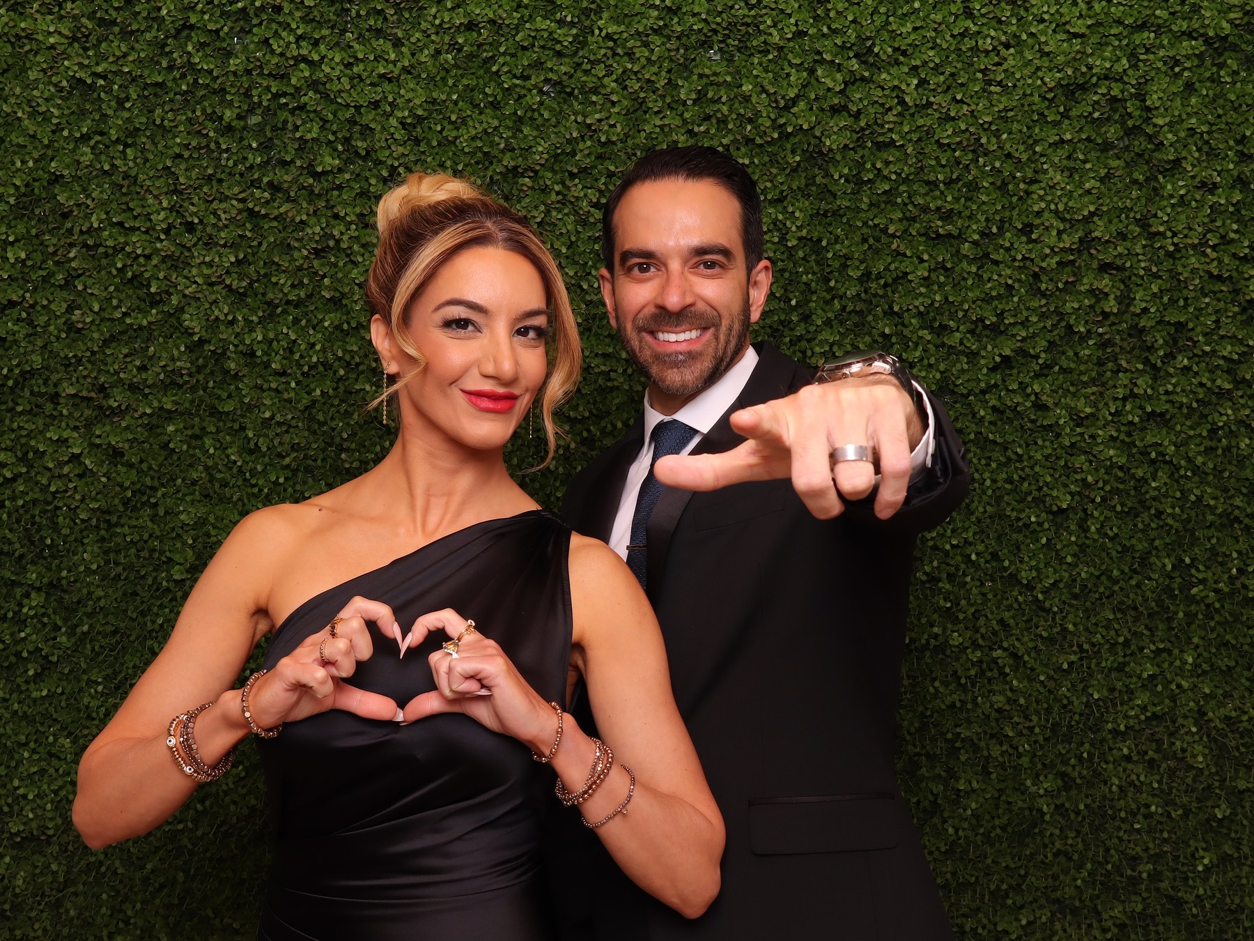 Wedding guests posing together in front of a greenery photo booth backdrop