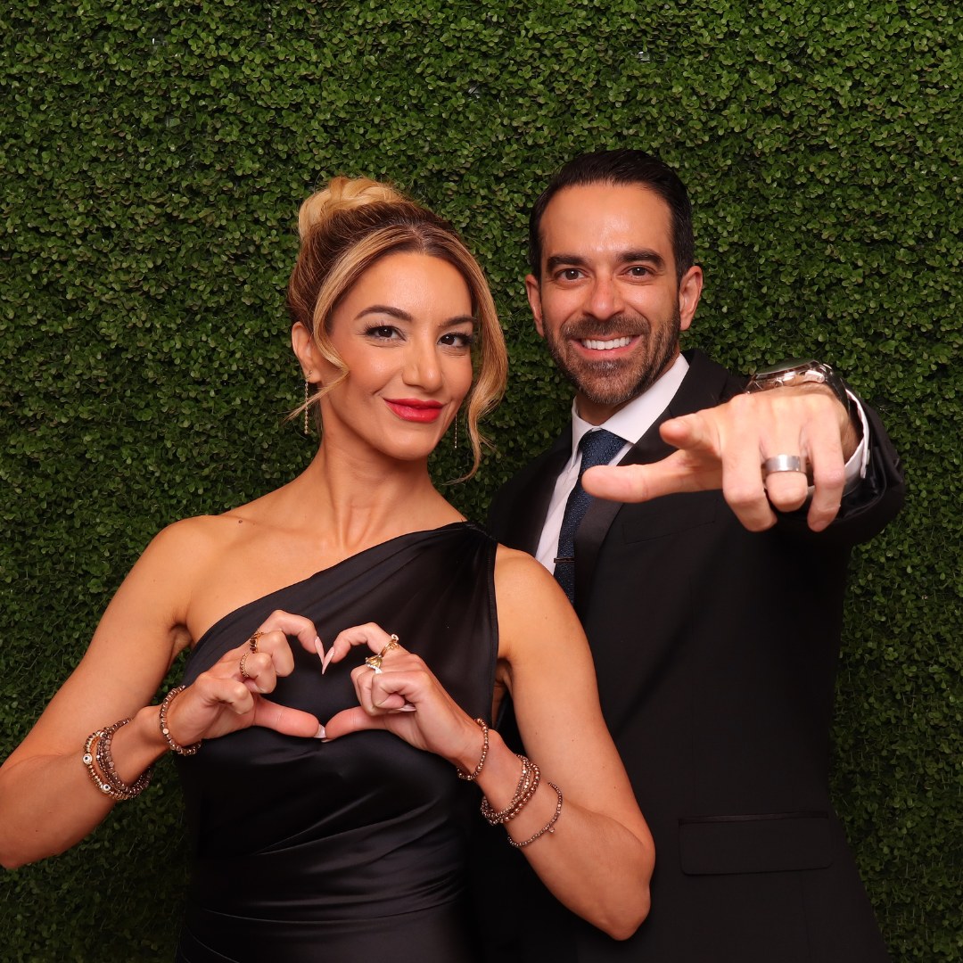 Couple dressed in black posing at a green wall