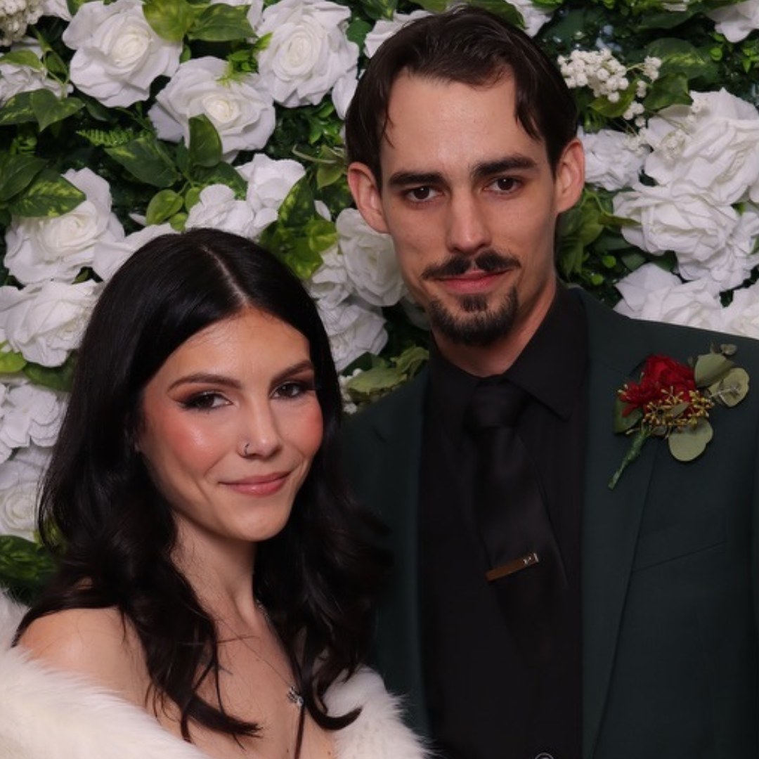 Couple posing in front of a flower wall