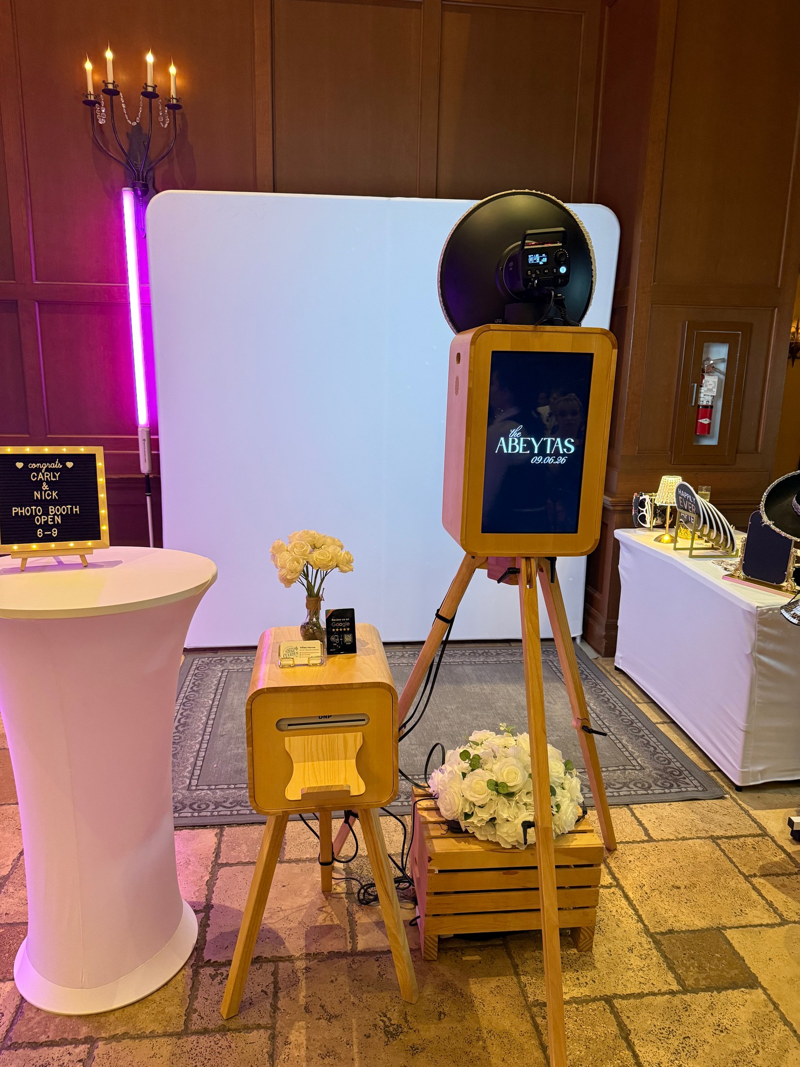 The Artisan oak Photo Booth and matching printer beside a white backdrop at a wedding