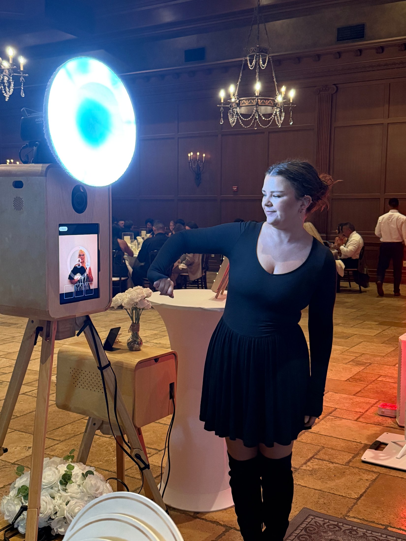 Guest using The Artisan oak Photo Booth with its illuminated ring light at a reception