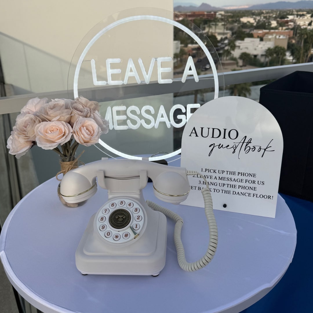 White Audio Guestbook phone on a styled station with flowers and a leave-a-message sign