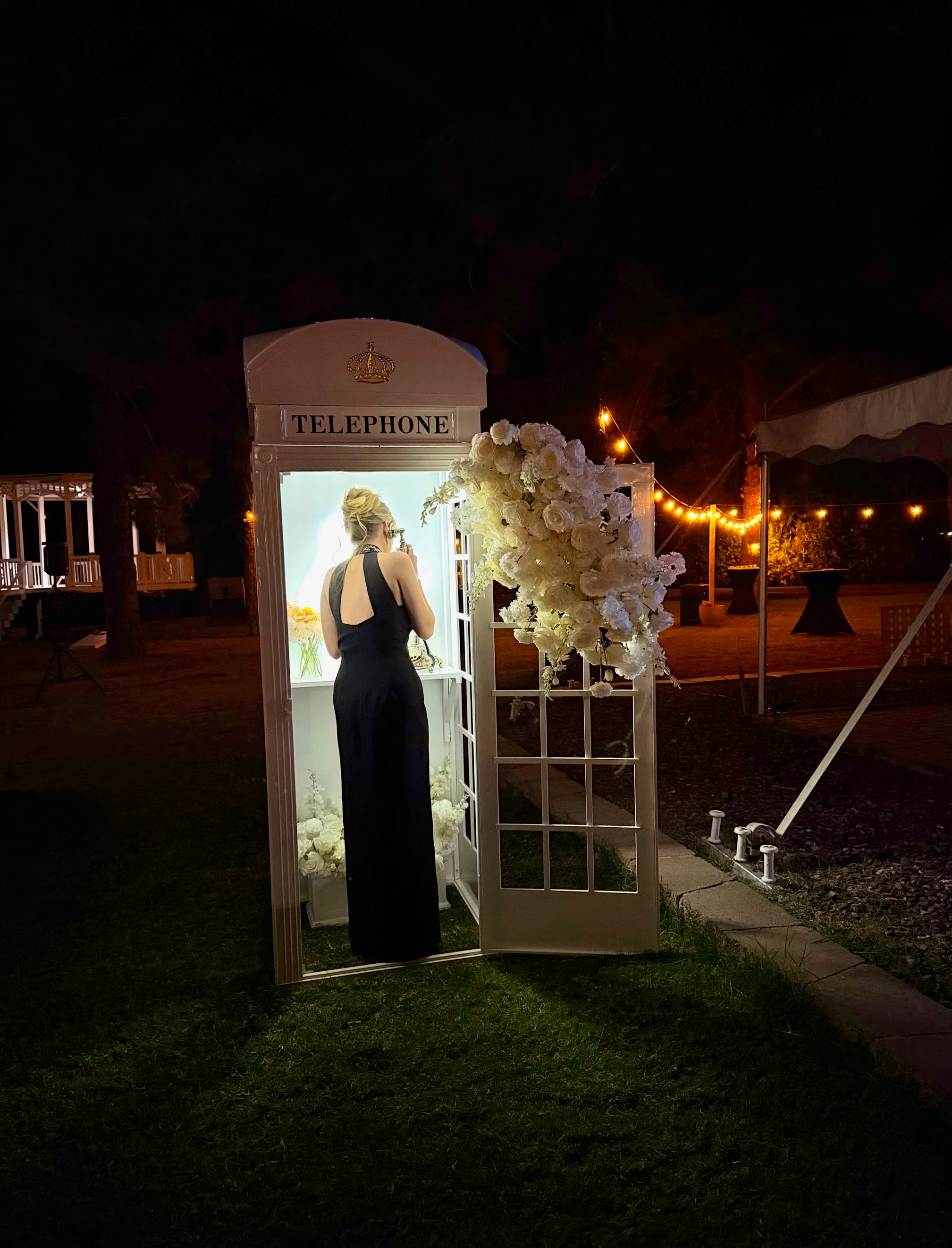 Wedding guest using a floral telephone booth Audio Guestbook at an outdoor reception