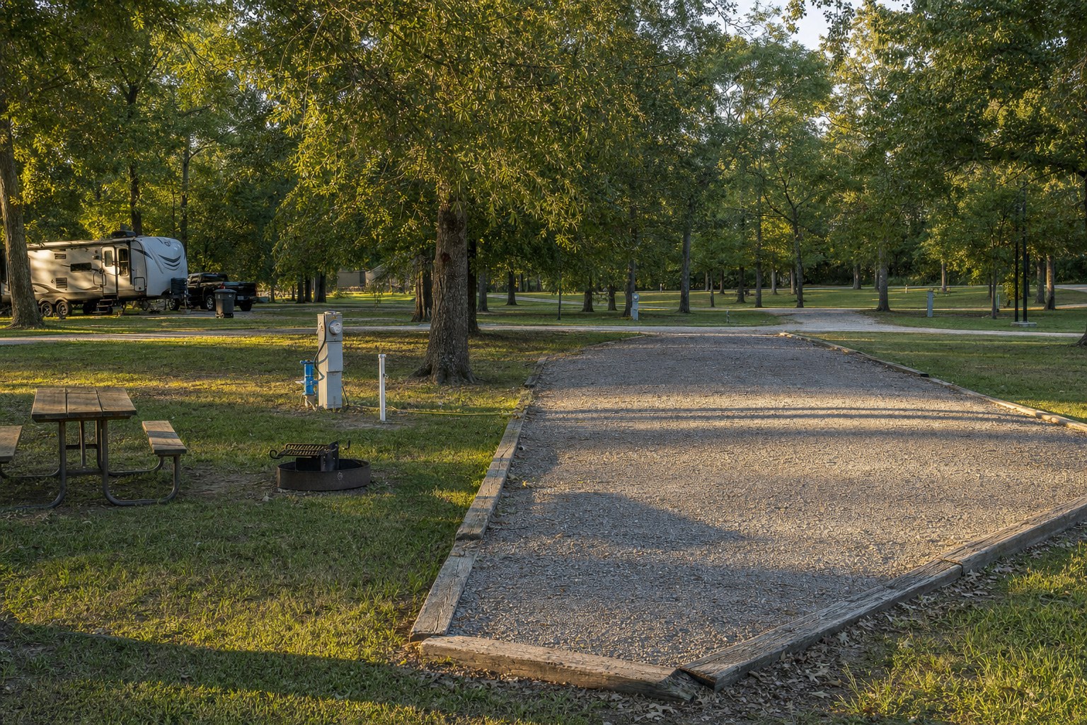 RV campsite showing a level pad, hookups, picnic table, and fire ring