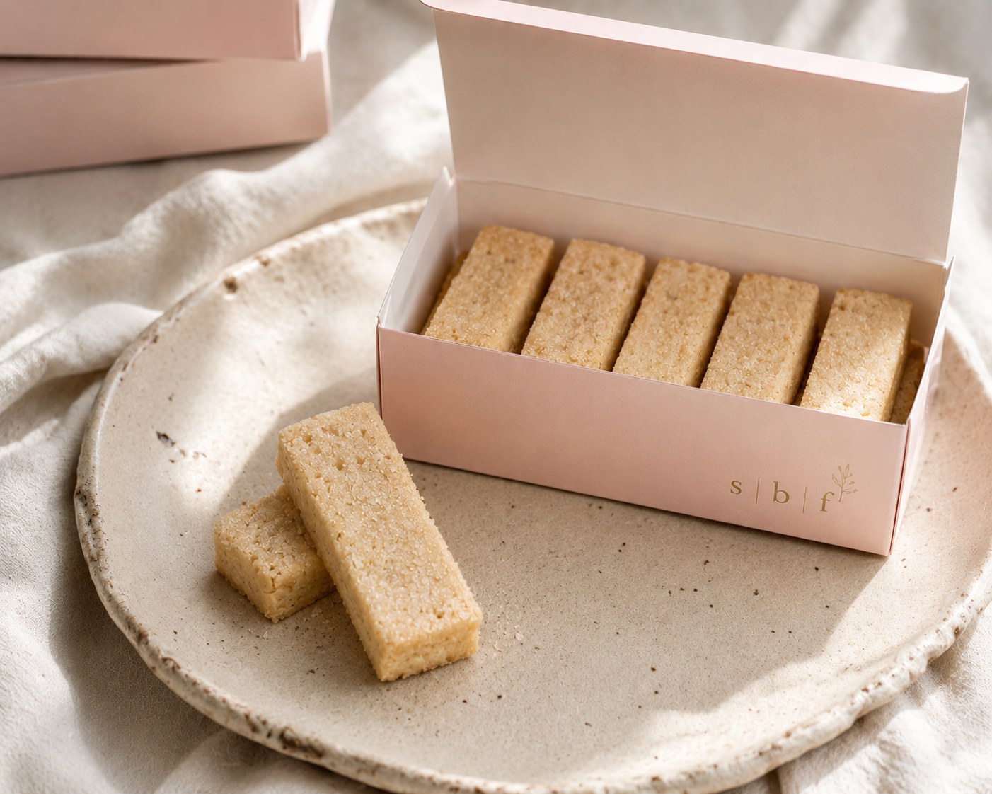 An open Sugar Butter Flower box filled with golden biscuits on a ceramic plate
