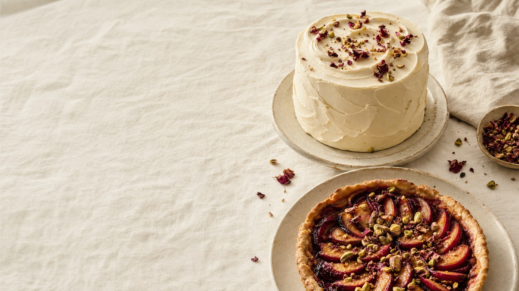 A frosted cake and fruit tart on linen