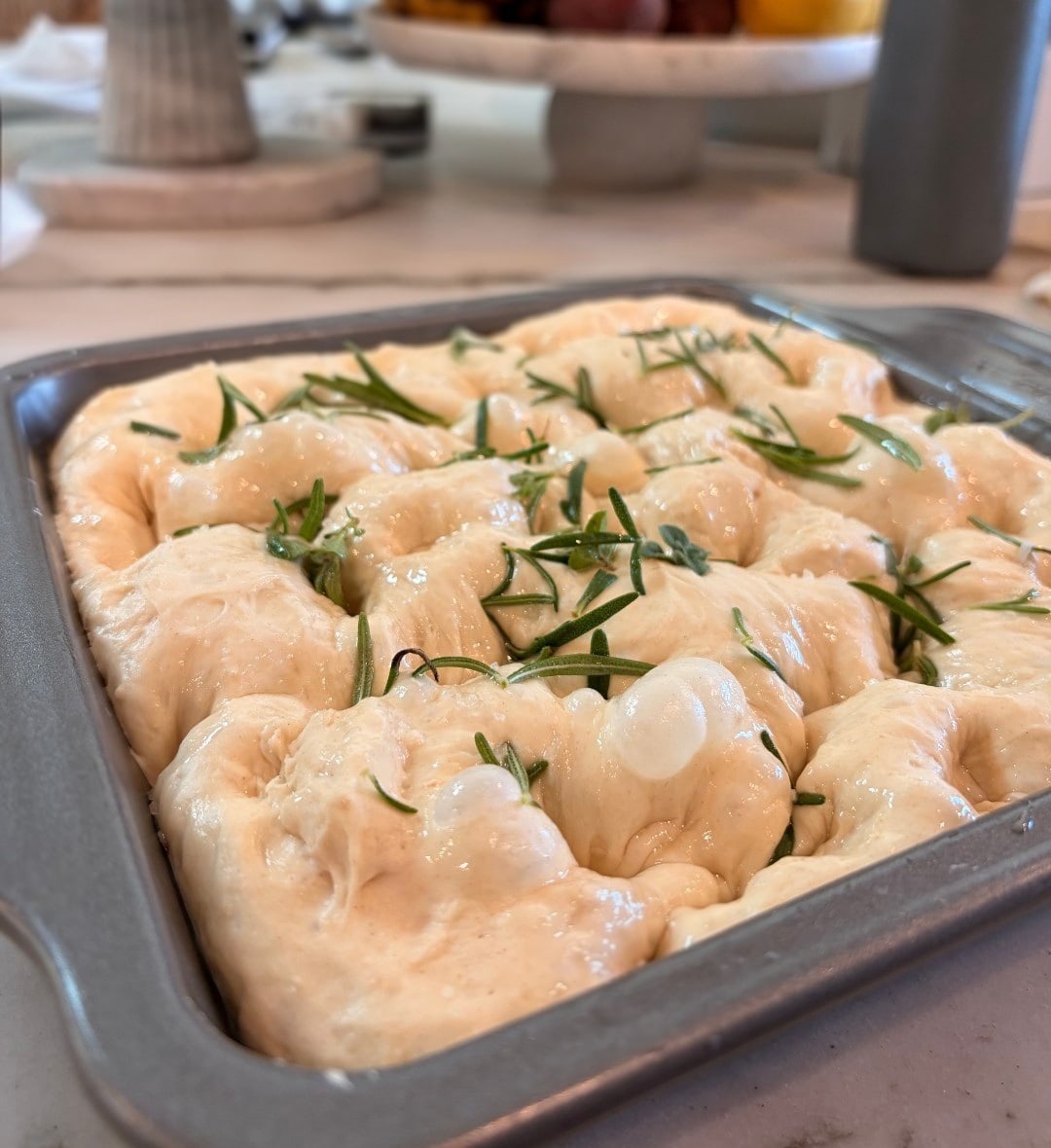 Rosemary focaccia dough rising in its pan before baking