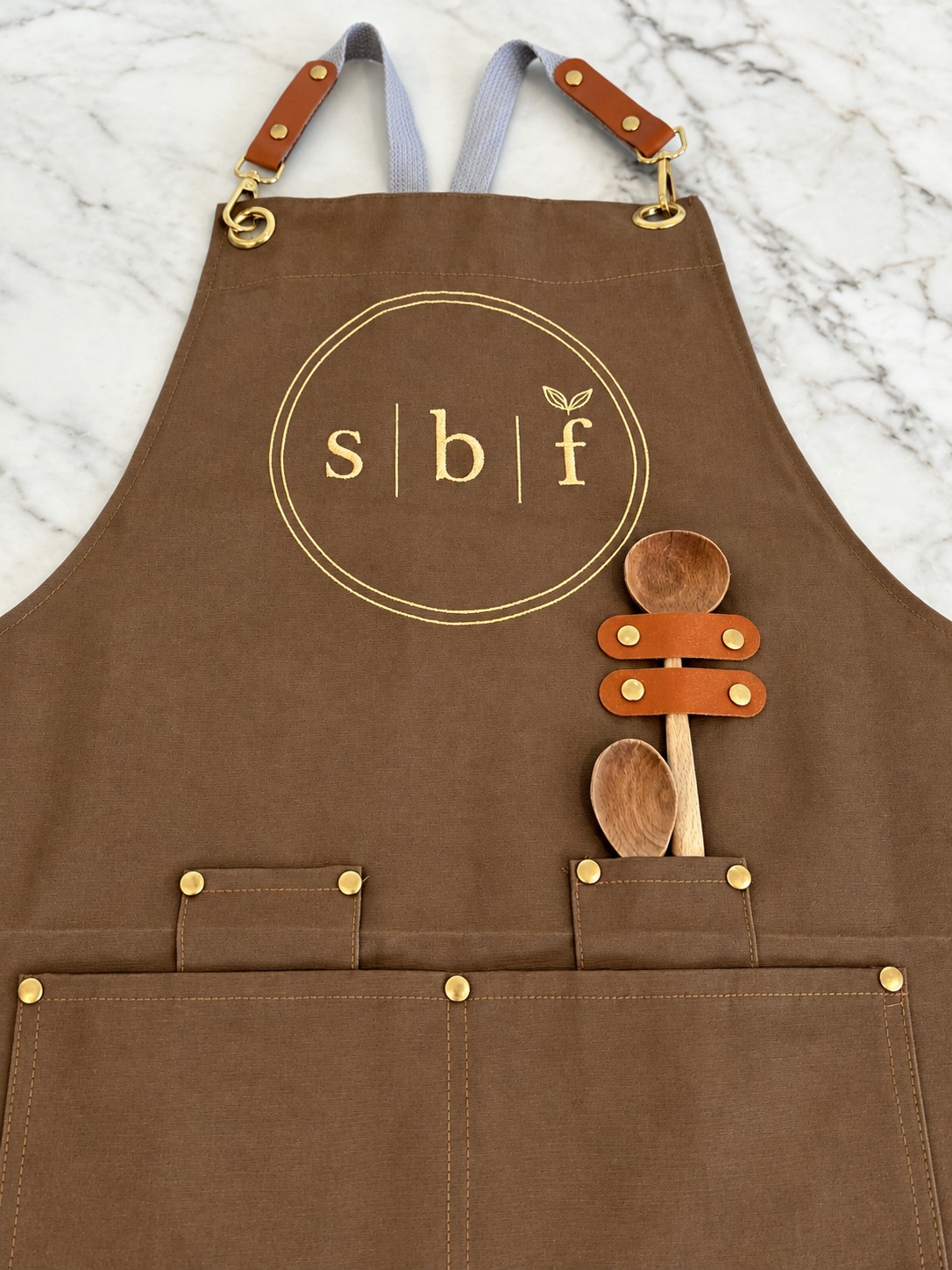 The embroidered sugar butter flower apron with leather straps and wooden spoons