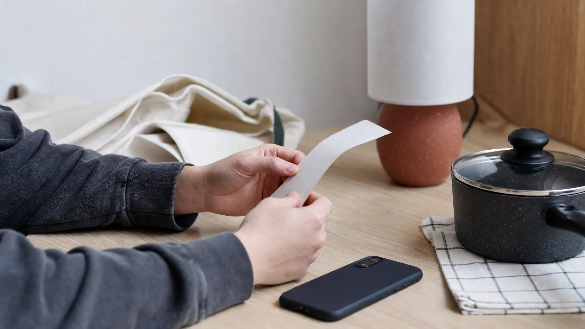 Student checking a receipt and final price beside a phone and homewares