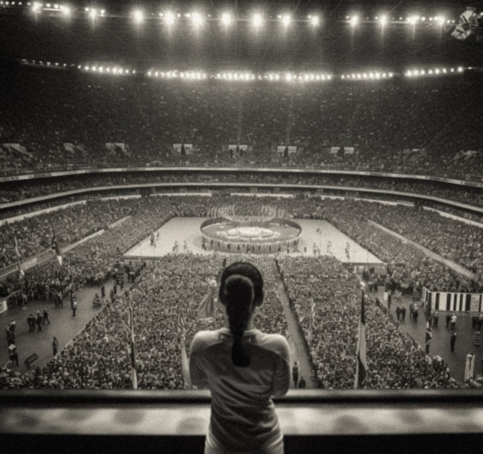 An athlete looking out over a floodlit stadium at night