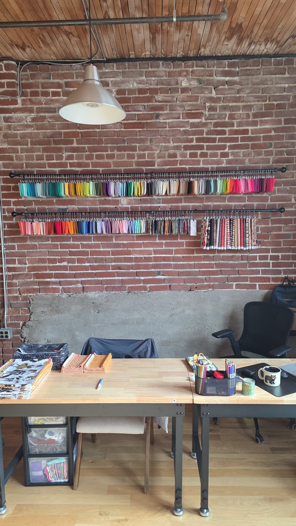Colorful fabric swatches on a brick wall above the cutting tables in the Bear Paws Creative studio