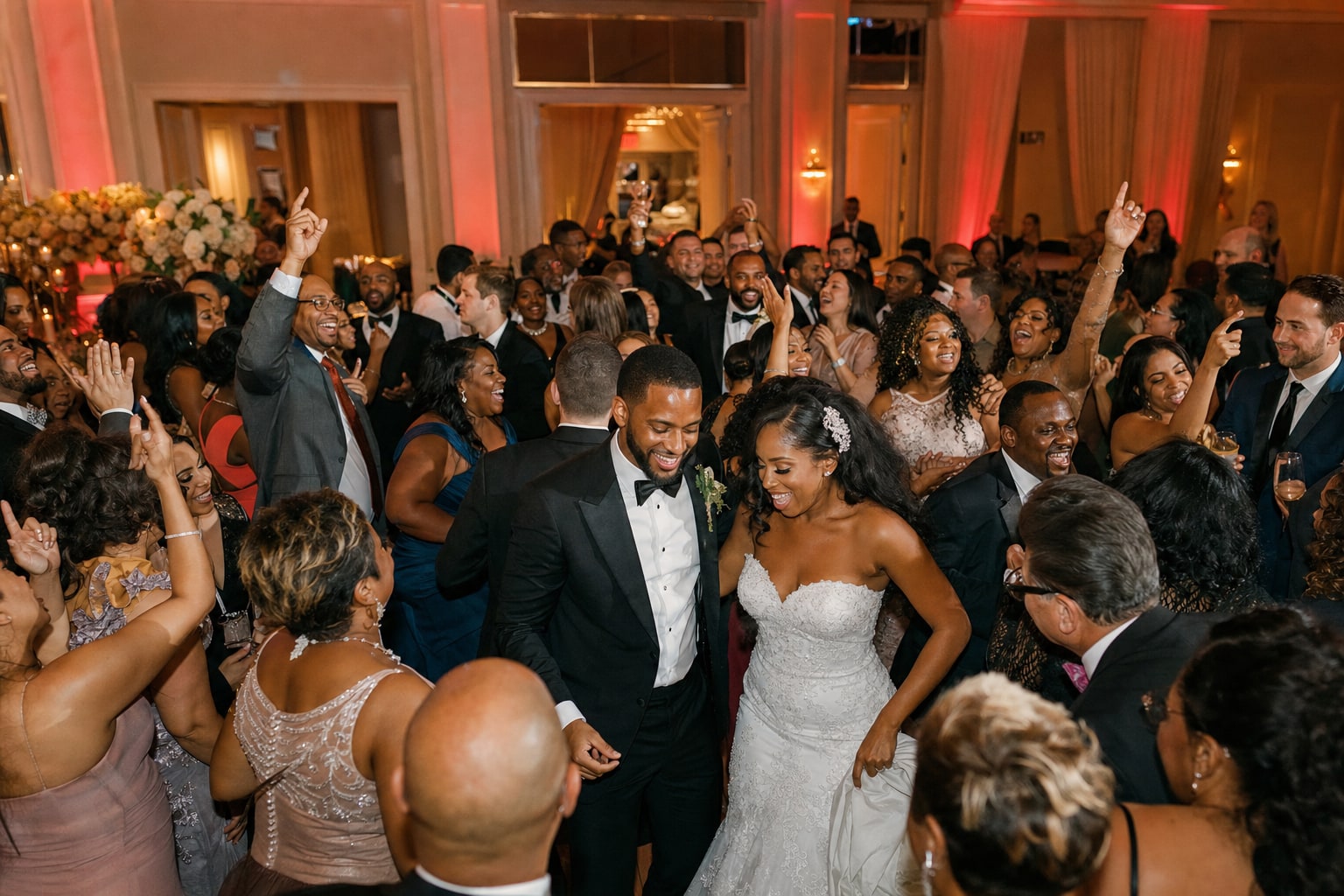 Newlyweds celebrating at the center of a packed wedding dance floor