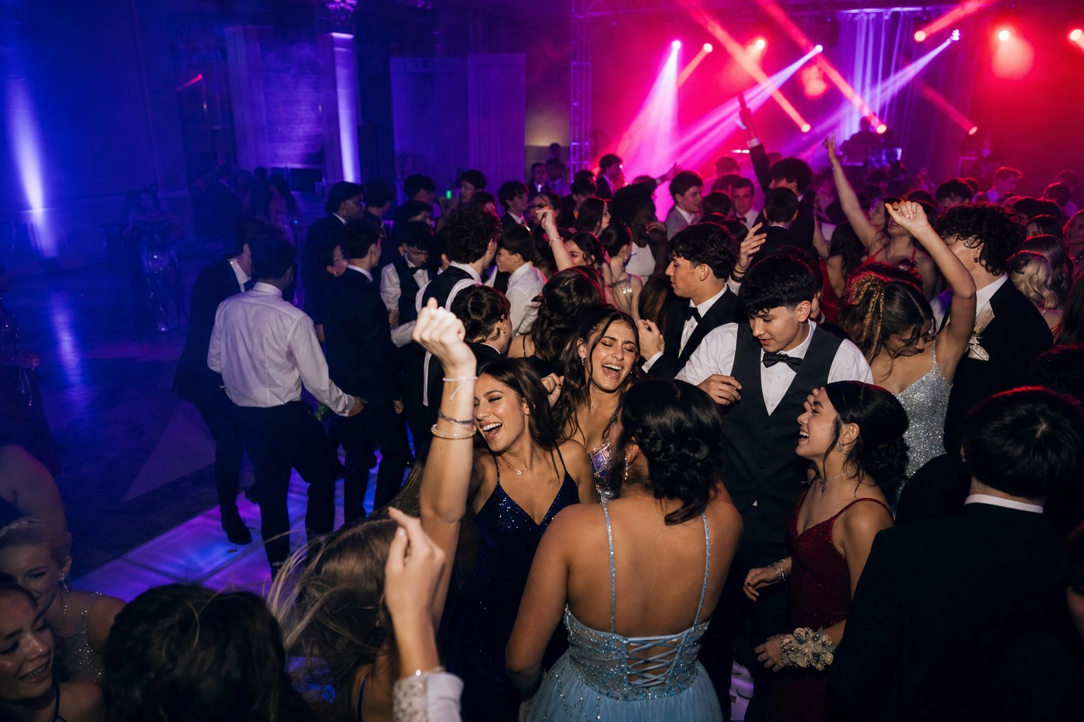 Packed high school prom dance floor under club-style lighting