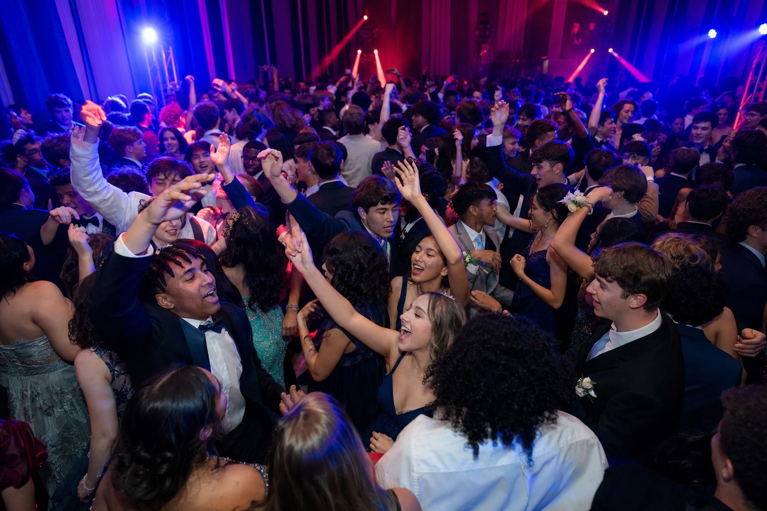 Packed prom dance floor under club-style lighting