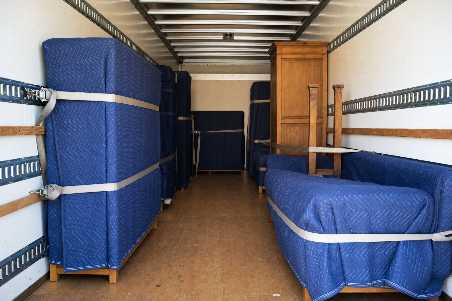 Furniture protected with moving blankets and secured inside a moving truck