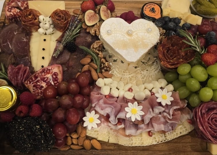 Detail of the engagement party board with heart-shaped cheese and small white flowers