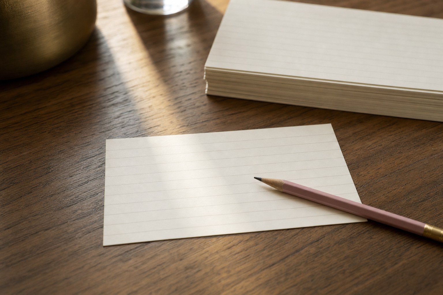 A blank index card and pencil on a warm wood desk