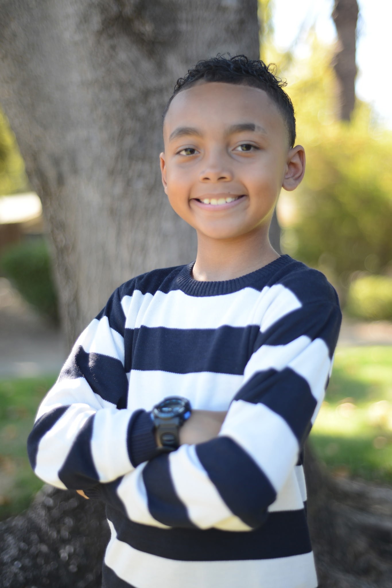 A boy standing beside a tree during a family session