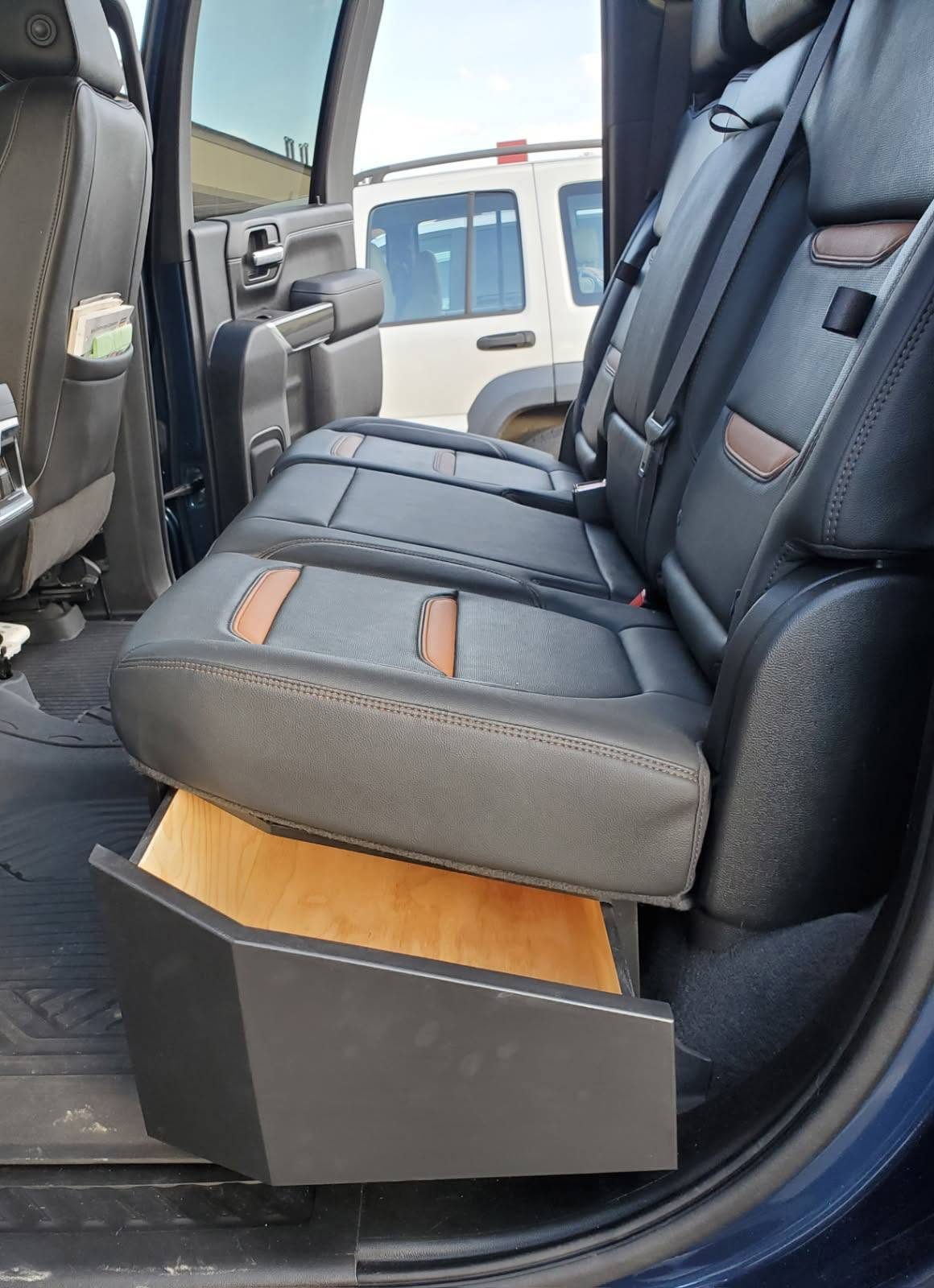 Wood storage drawer fitted beneath a truck's rear seats