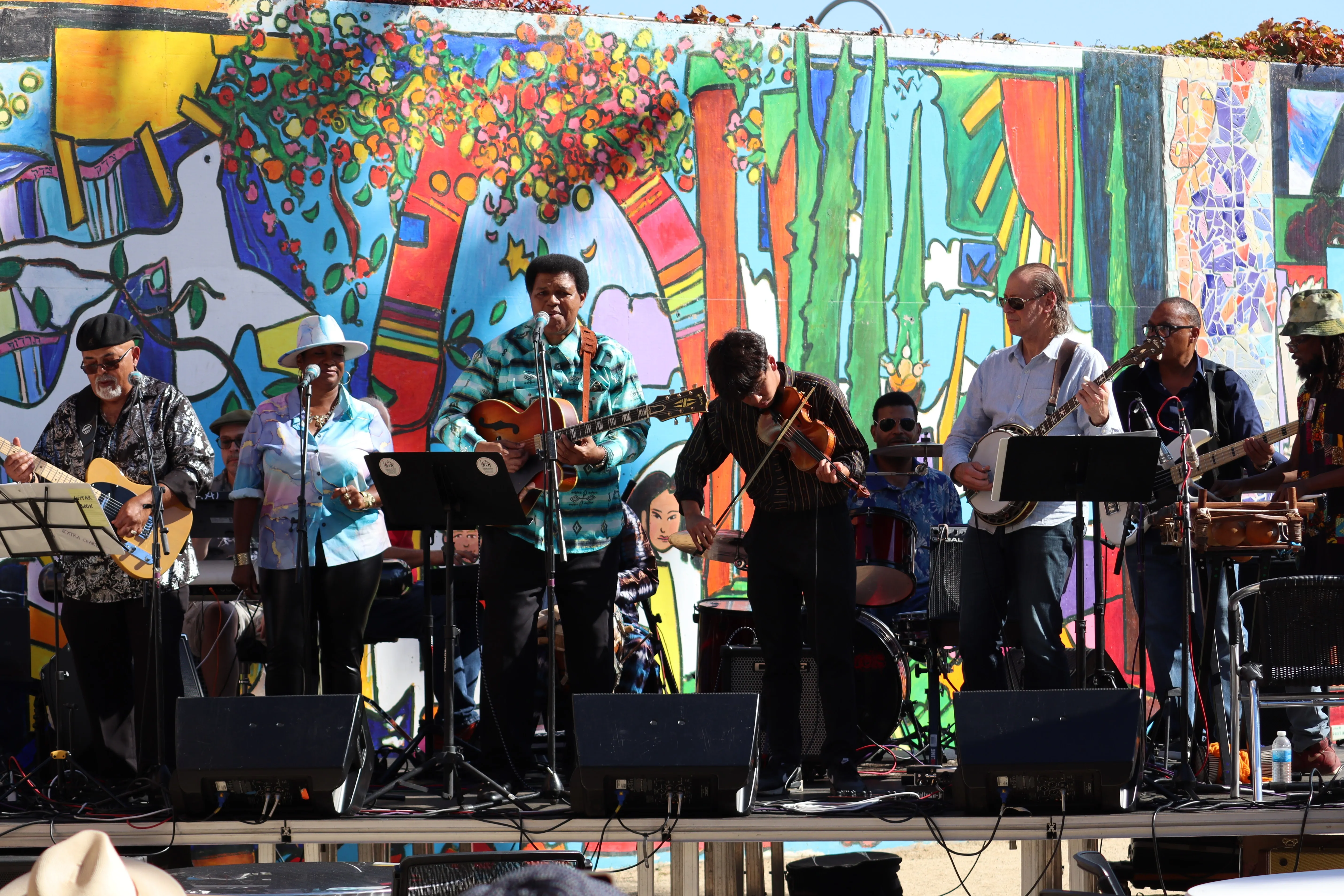 Pascal Bokar AfroBlueGrazz Band performing on a mural-backed festival stage