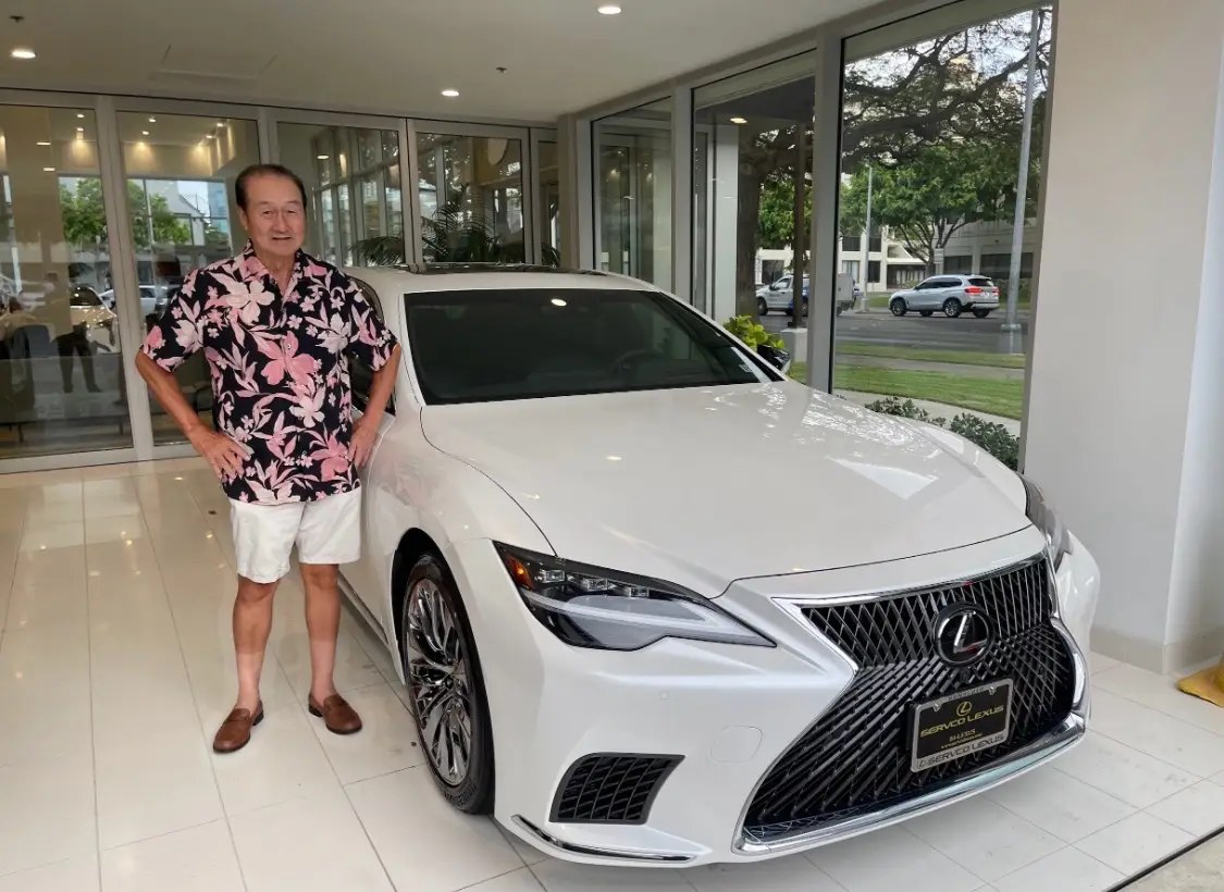 A mature man standing beside a white sedan
