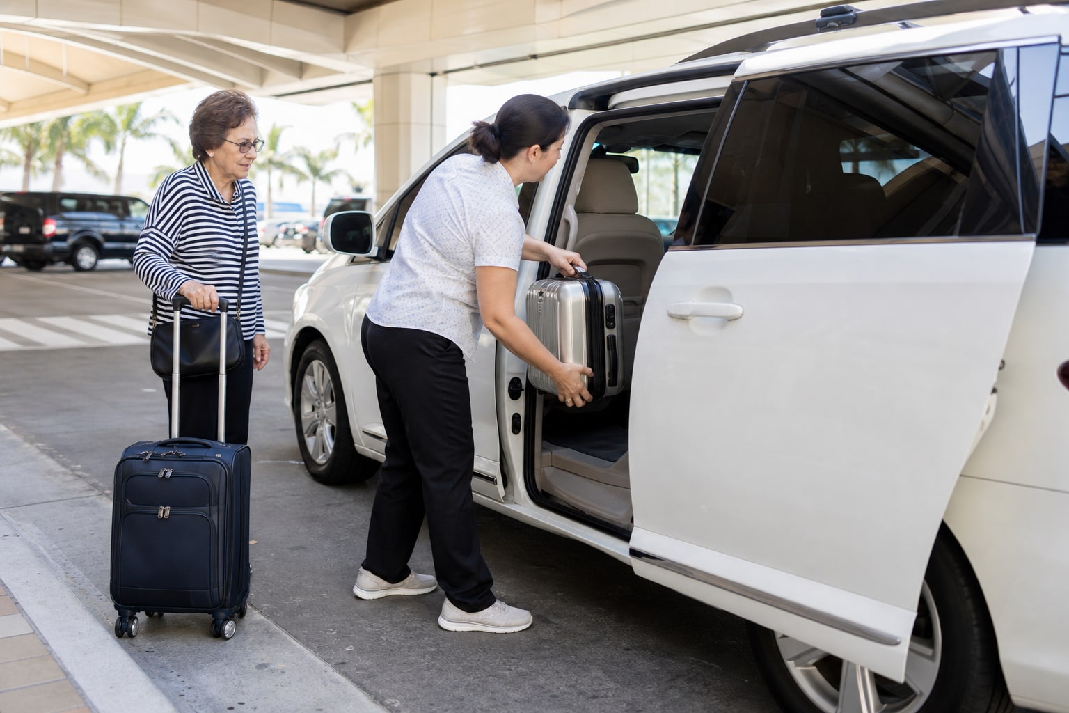 A female driver loading luggage into a white passenger minivan