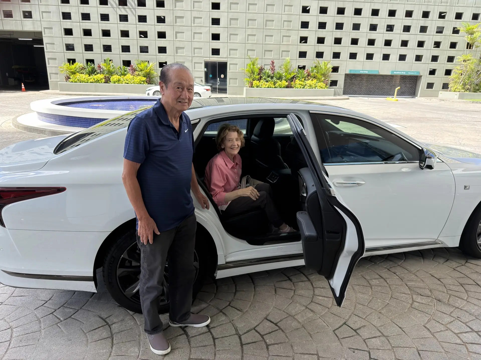 A Kupuna LIMO member-client beside a white sedan
