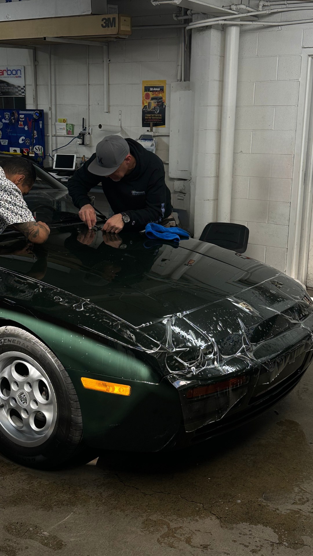 Technician working on a black vehicle during paint protection film installation