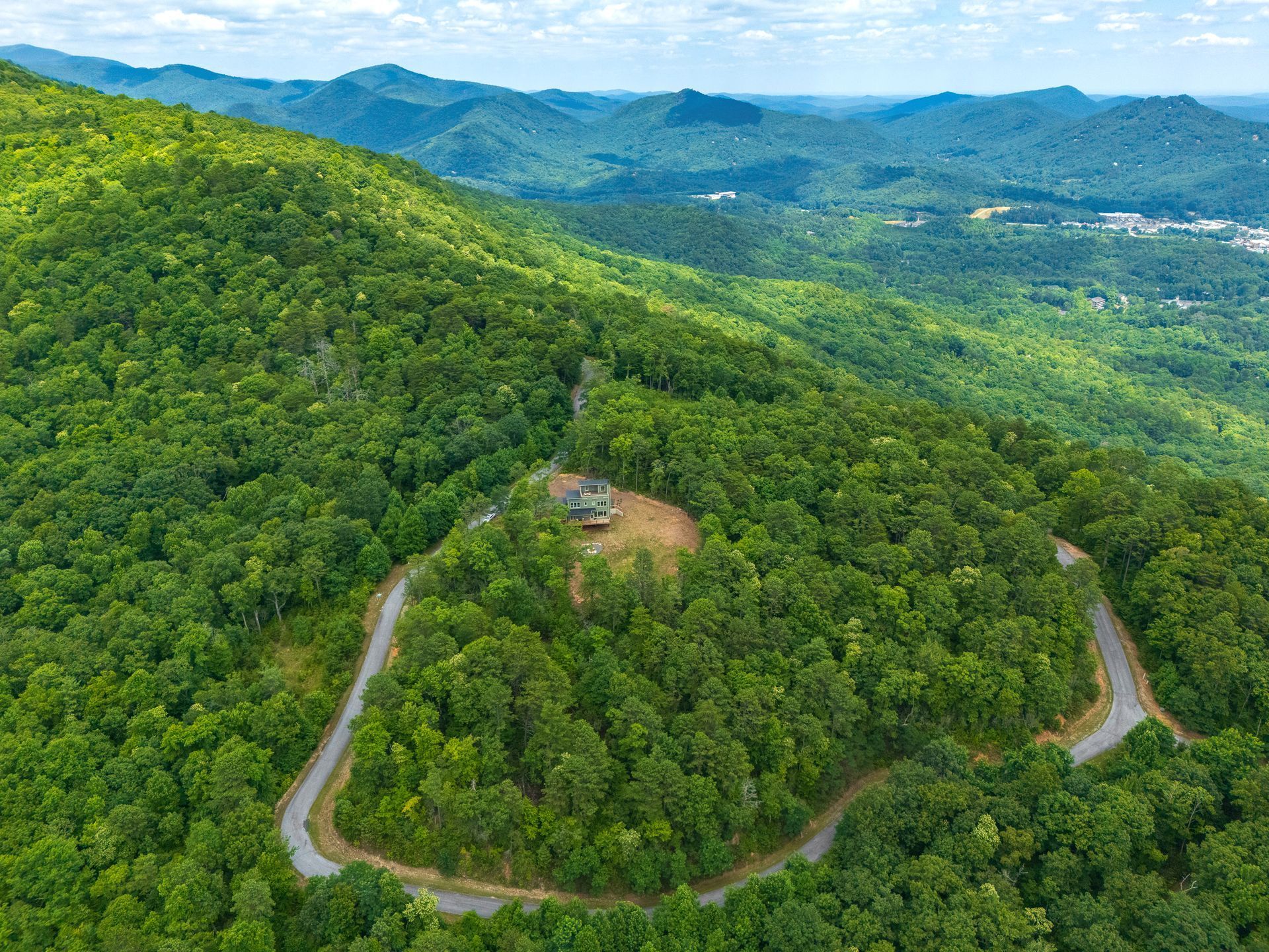 Aerial view of winding road through lush, green mountain forest.