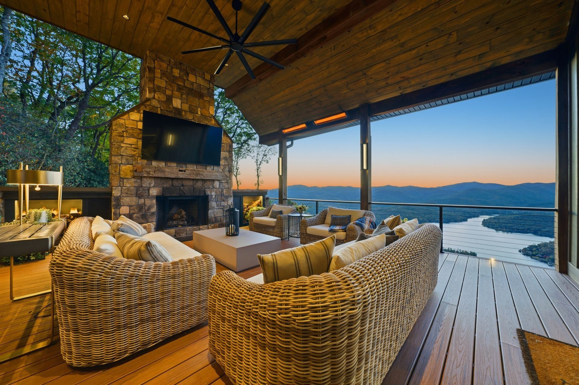 Covered vacation rental deck with a fireplace, seating, and lake views