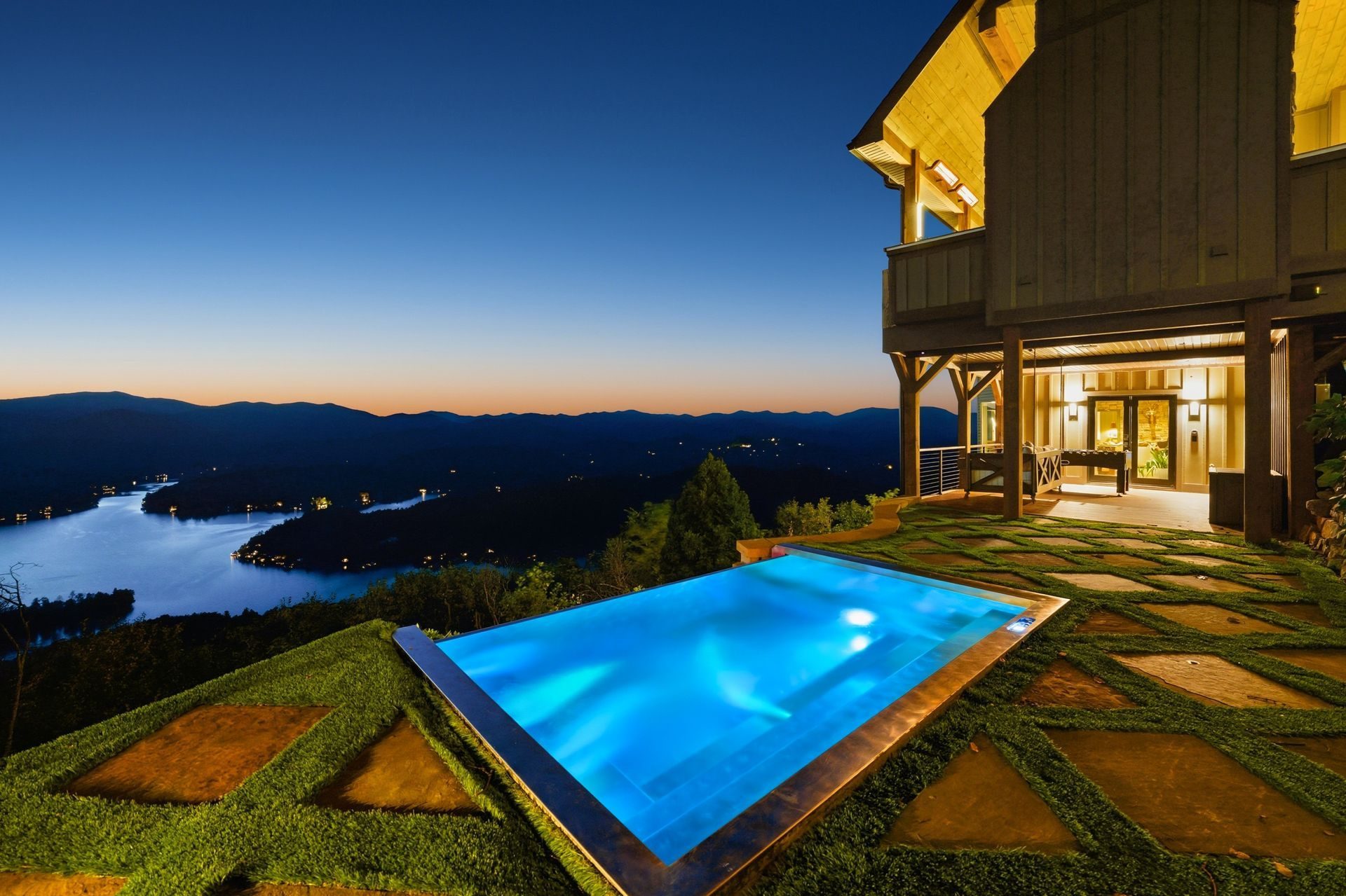 Illuminated pool beside a vacation rental overlooking a lake