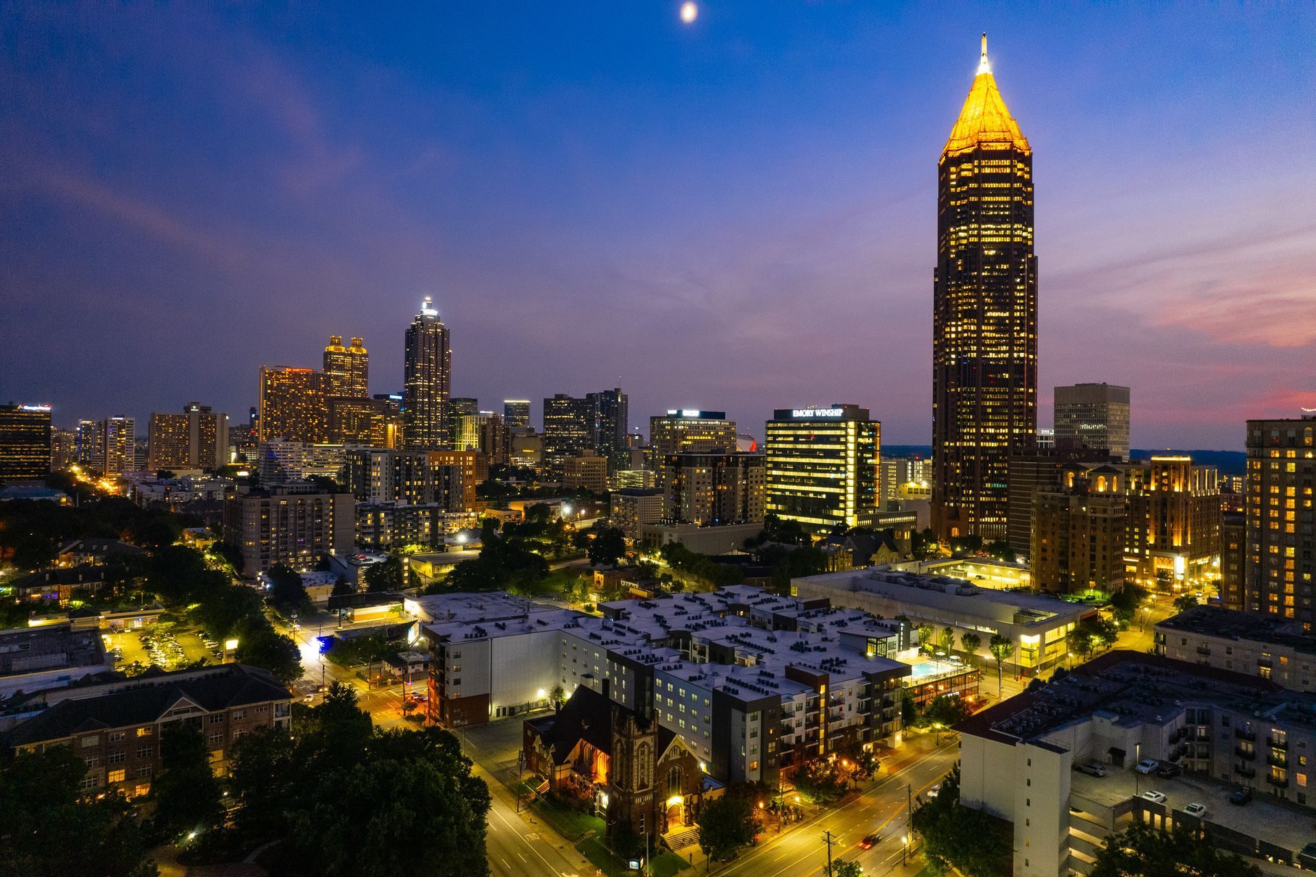 An aerial view of a city at night with a tall building in the foreground.