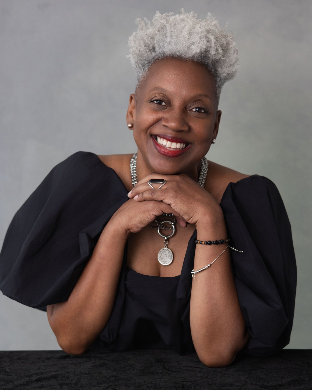 Studio portrait of a smiling woman with silver hair in a black top
